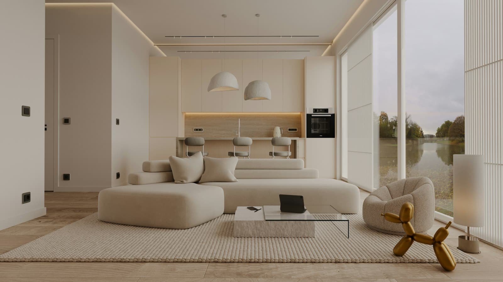 A bright cream-toned open-plan living space with a large sofa and floor-to-ceiling windows looking onto water.